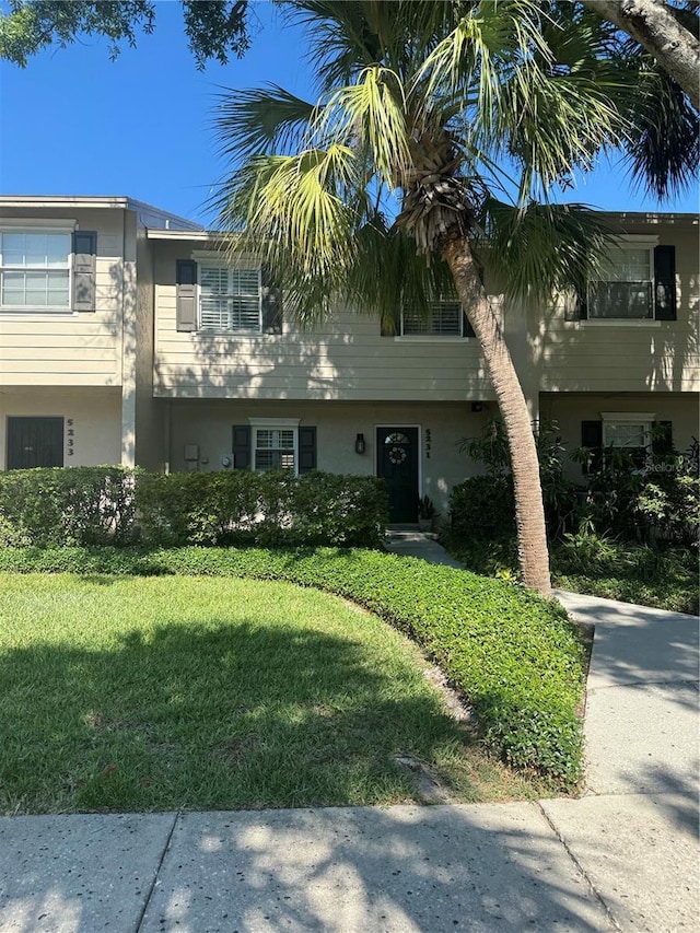 multi unit property with stucco siding and a front yard