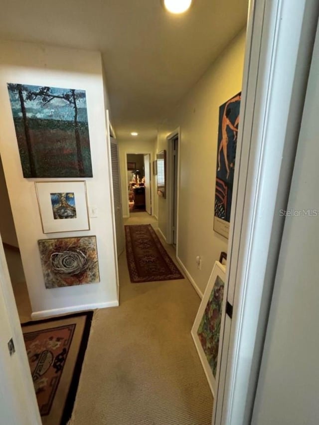 corridor featuring baseboards and carpet flooring