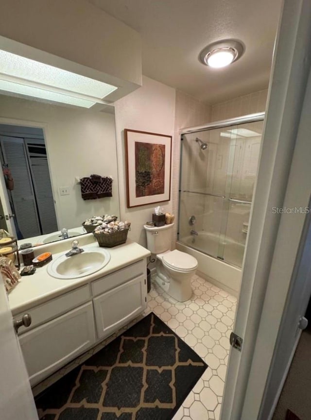 full bath with enclosed tub / shower combo, vanity, toilet, and tile patterned floors