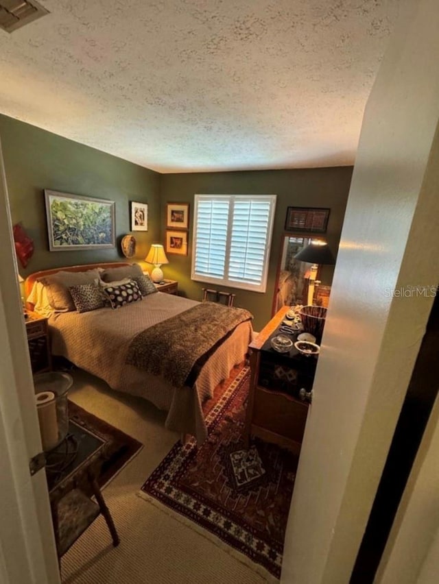 carpeted bedroom featuring a textured ceiling and visible vents