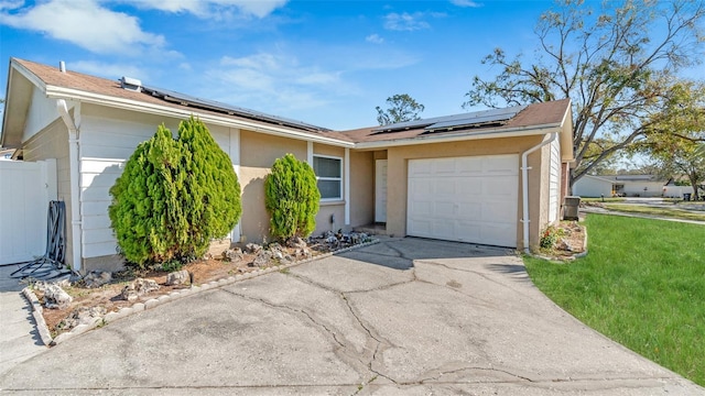 single story home featuring a garage, driveway, a front lawn, and solar panels