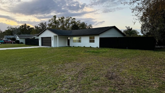 single story home featuring driveway, a lawn, and an attached garage