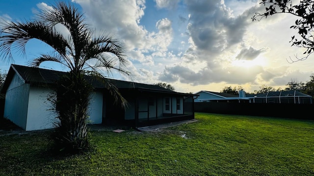 back of house with fence, a lawn, and stucco siding