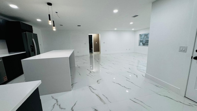 kitchen featuring recessed lighting, dark cabinets, refrigerator with ice dispenser, marble finish floor, and light countertops