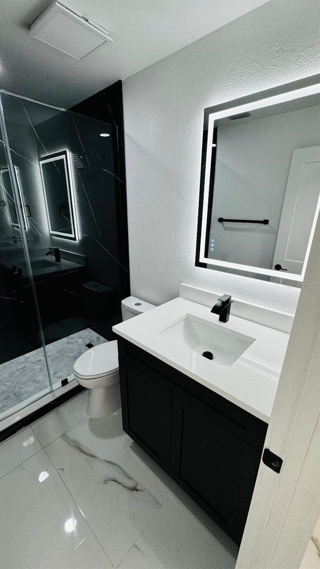 full bath featuring a textured wall, toilet, marble finish floor, vanity, and a shower stall
