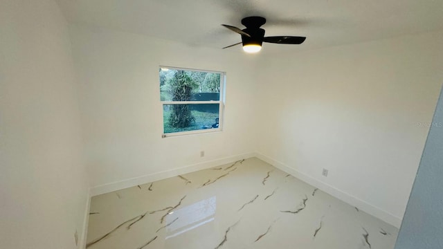 unfurnished room featuring marble finish floor, ceiling fan, and baseboards