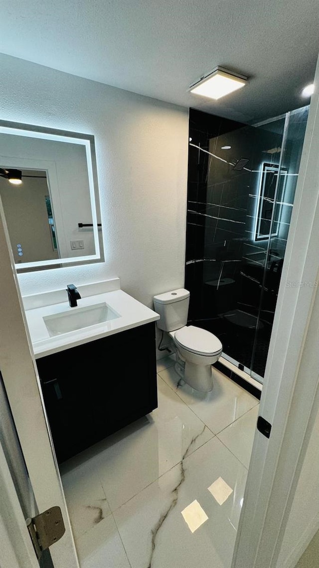 bathroom with marble finish floor, a marble finish shower, vanity, and toilet