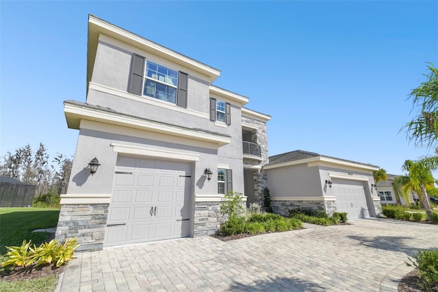 view of front facade featuring stone siding, decorative driveway, and stucco siding