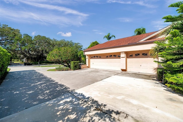 view of side of home featuring a garage and stucco siding