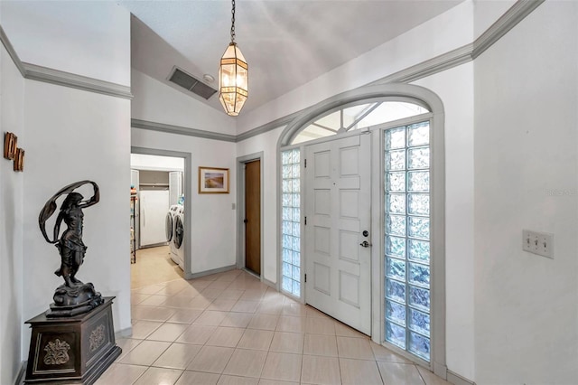 foyer entrance with light tile patterned floors, visible vents, baseboards, ornamental molding, and washer and clothes dryer