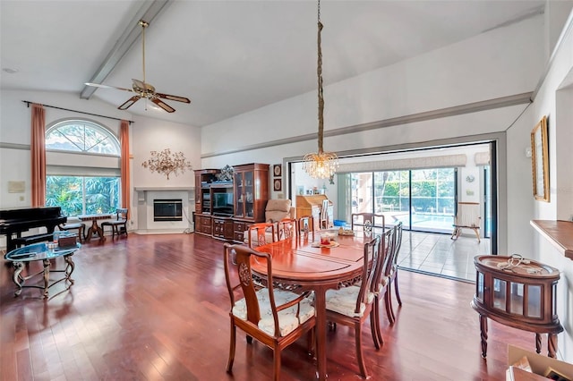 dining area with a glass covered fireplace, beam ceiling, plenty of natural light, and wood finished floors