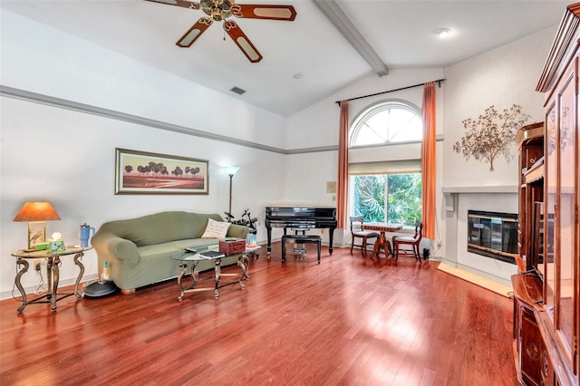 living room featuring high vaulted ceiling, wood finished floors, visible vents, beam ceiling, and a glass covered fireplace