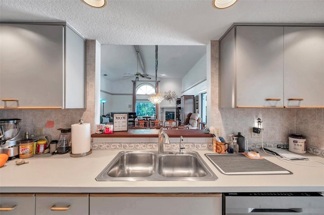 kitchen featuring lofted ceiling, dishwasher, light countertops, and a sink