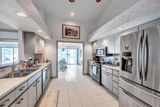 kitchen featuring recessed lighting, light countertops, appliances with stainless steel finishes, a sink, and baseboards