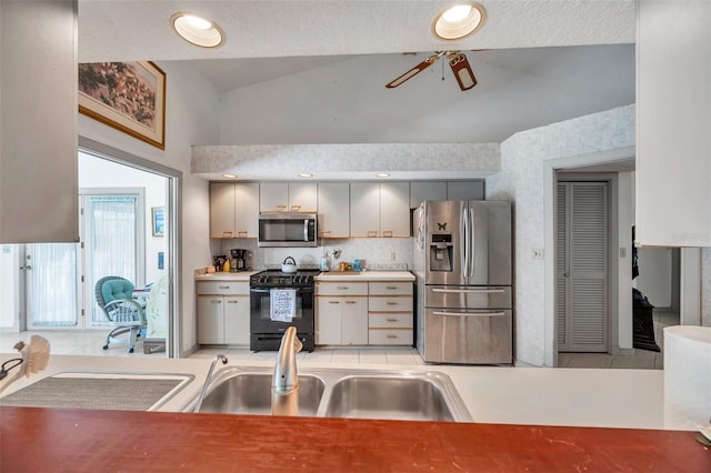 kitchen with tasteful backsplash, lofted ceiling, gray cabinetry, appliances with stainless steel finishes, and ceiling fan