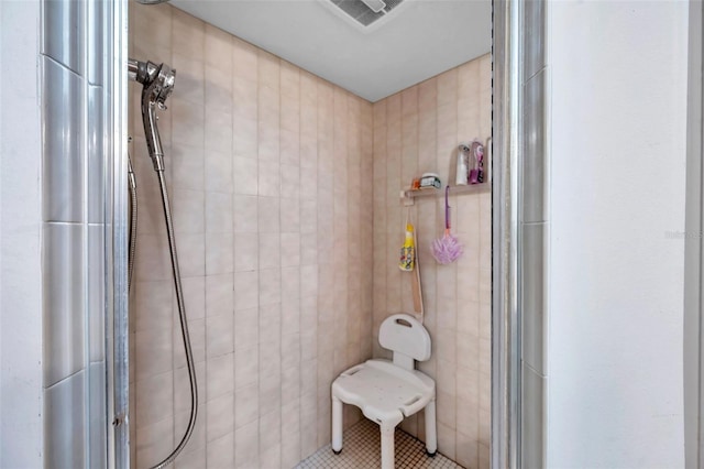 full bathroom featuring tile patterned flooring, visible vents, a tile shower, and tile walls