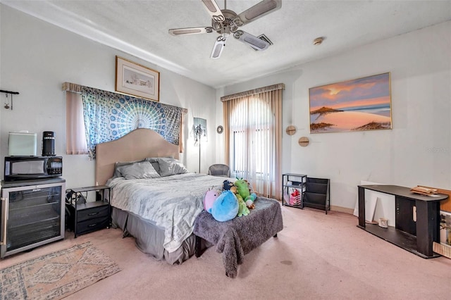 bedroom featuring a textured ceiling, wine cooler, a ceiling fan, and light colored carpet