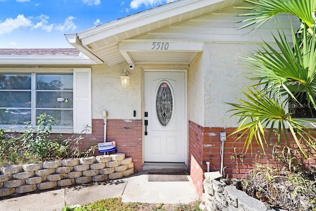 property entrance featuring brick siding and stucco siding