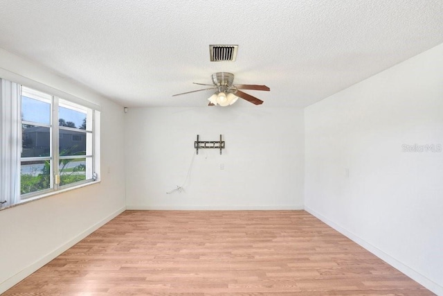 spare room featuring visible vents, ceiling fan, a textured ceiling, light wood-type flooring, and baseboards