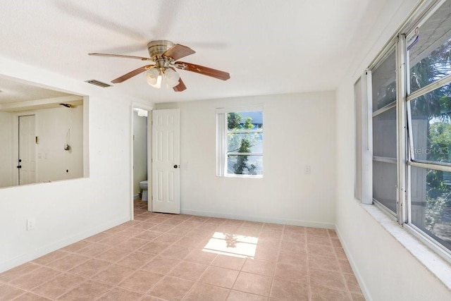 unfurnished room with light tile patterned floors, baseboards, visible vents, and ceiling fan