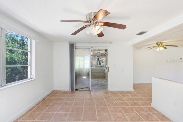 spare room featuring light tile patterned floors, visible vents, and baseboards