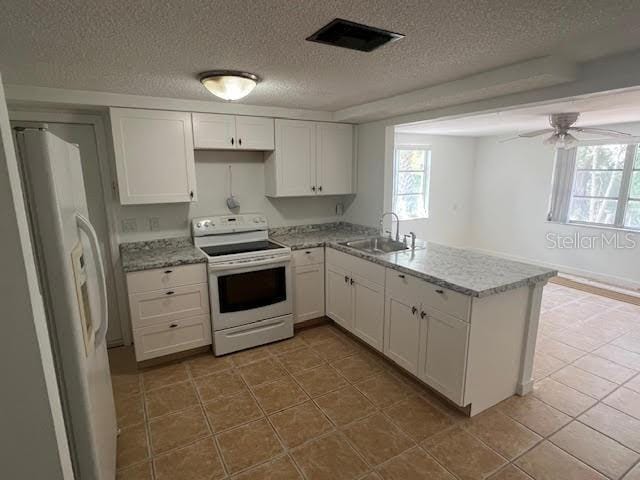 5510 Berlin Dr, Port Richey, FL 34668 - kitchen with white cabinets, a sink, white appliances, a peninsula, and a textured ceiling