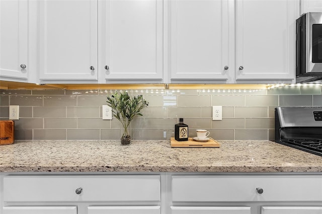 17541 Corkwood Bend Trl, Punta Gorda, FL 33982 - kitchen with white cabinets, backsplash, and light stone countertops