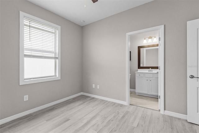 17541 Corkwood Bend Trl, Punta Gorda, FL 33982 - unfurnished bedroom with light wood finished floors, baseboards, connected bathroom, and a sink
