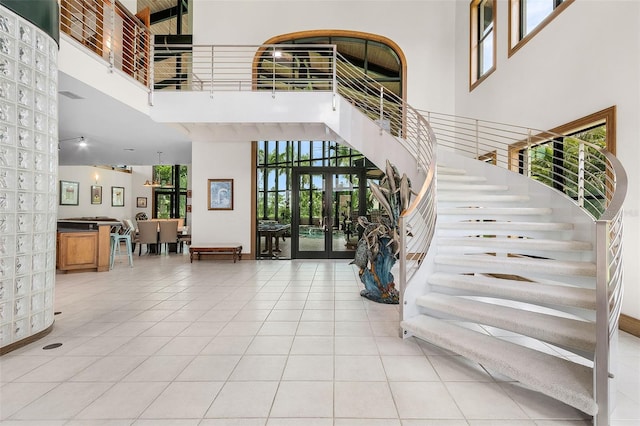 tiled foyer entrance featuring a wealth of natural light, stairway, and a high ceiling