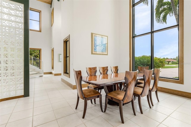 dining area featuring stairs, a high ceiling, baseboards, and light tile patterned flooring