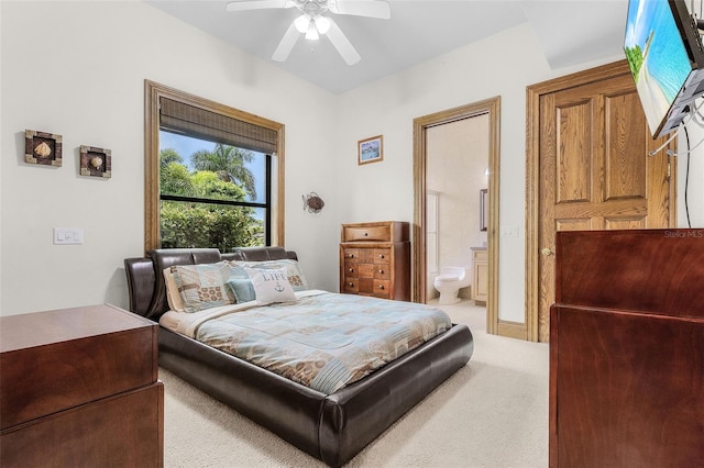 bedroom with a ceiling fan, light colored carpet, and ensuite bath