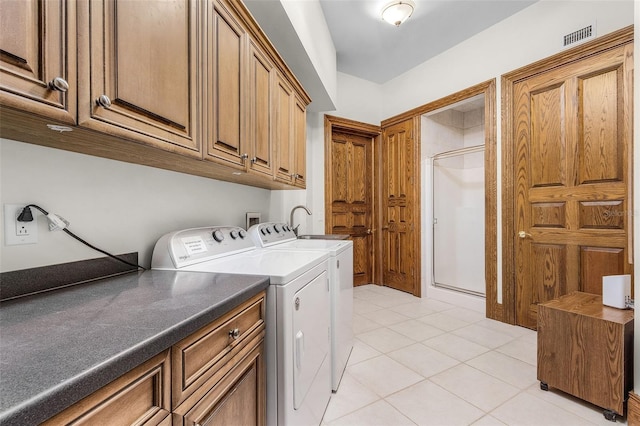 clothes washing area featuring visible vents, light tile patterned flooring, washing machine and clothes dryer, and cabinet space