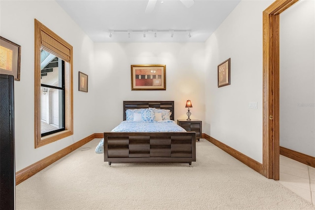 bedroom with rail lighting, light colored carpet, and baseboards