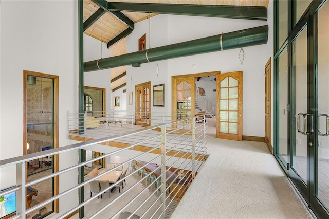 interior space featuring baseboards, beamed ceiling, carpet, french doors, and high vaulted ceiling