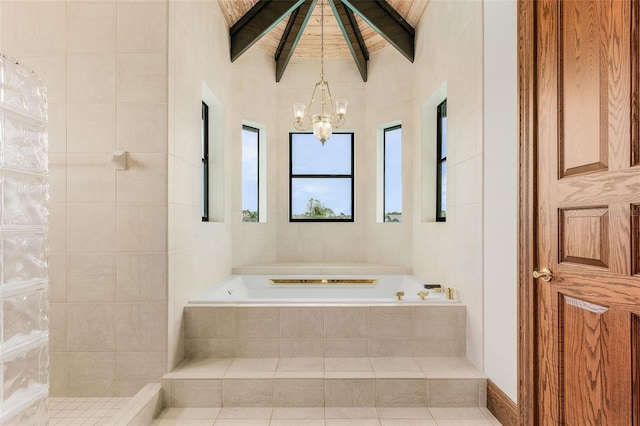 bathroom with a chandelier, beamed ceiling, a garden tub, and tile walls