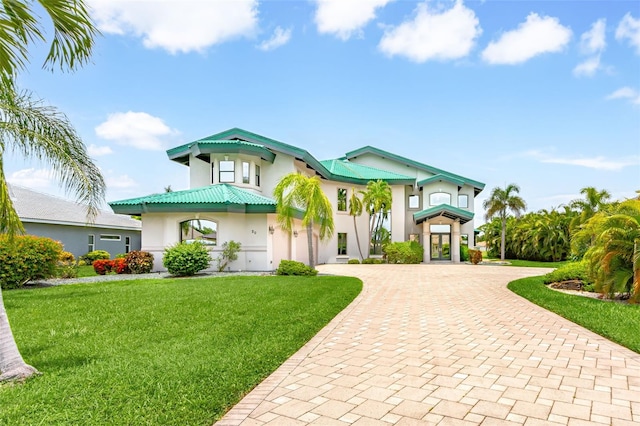 view of front facade featuring a front lawn, decorative driveway, and stucco siding