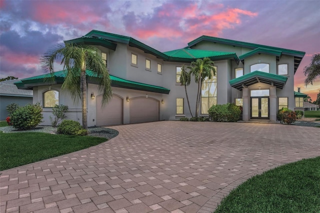 view of front of property featuring a garage, decorative driveway, french doors, and stucco siding