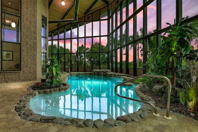 pool at dusk featuring glass enclosure and an outdoor pool