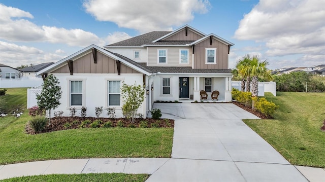 view of front of home featuring board and batten siding, a front yard, concrete driveway, and fence