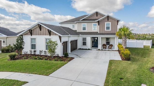 view of front of property with covered porch, board and batten siding, a front yard, fence, and driveway