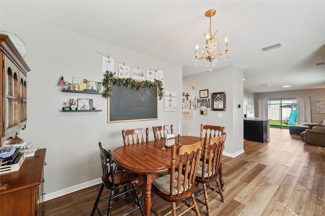 dining area featuring baseboards, visible vents, a chandelier, and wood finished floors