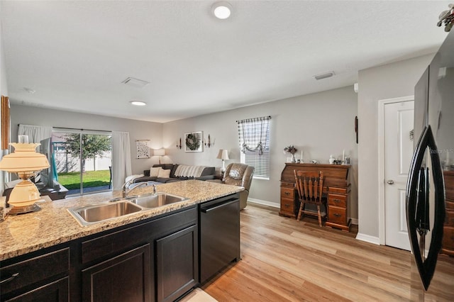 kitchen featuring light wood finished floors, open floor plan, a healthy amount of sunlight, a sink, and dishwasher