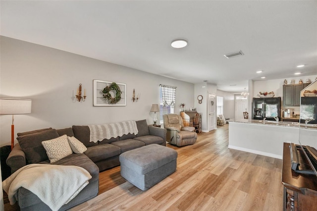 living room featuring light wood-style floors, visible vents, and baseboards