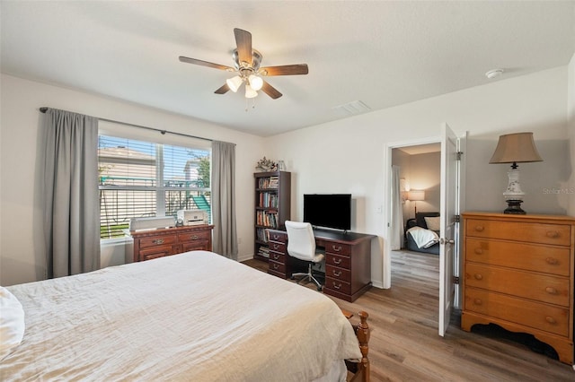 bedroom featuring baseboards, wood finished floors, visible vents, and a ceiling fan