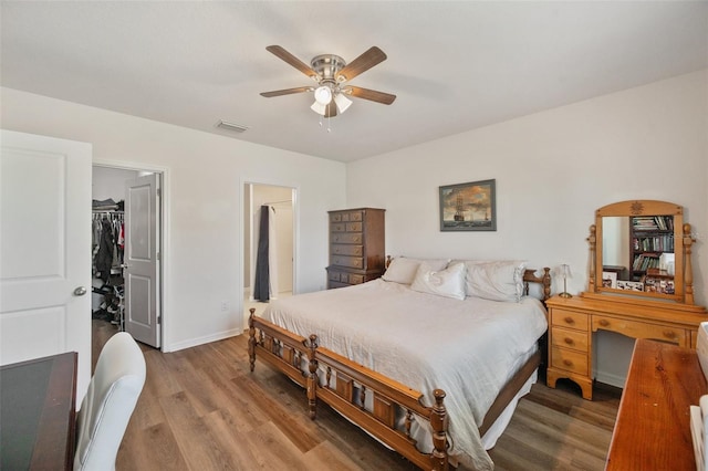 bedroom featuring a closet, visible vents, a spacious closet, wood finished floors, and baseboards