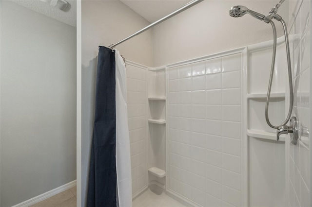 bathroom with a stall shower, baseboards, and tile patterned floors