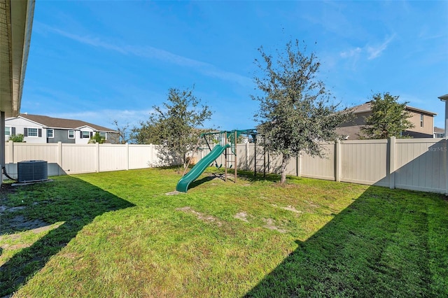 view of yard featuring a fenced backyard, a playground, and central air condition unit