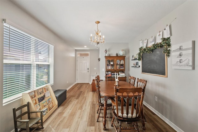 dining room with a notable chandelier, light wood finished floors, and baseboards