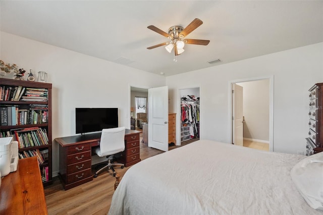 bedroom featuring ceiling fan, wood finished floors, visible vents, a spacious closet, and a closet