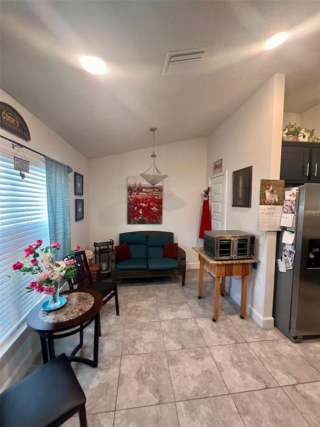 living area featuring light tile patterned flooring, visible vents, and baseboards